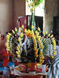 2015-05-13 Hochzeit von Njo und Loy. An dem Gesteck aus Bananenblättern hängen die Baumwollbändchen, die man sich später um die Handgelenke wickelt und Geldscheine. Drumherum stehen Getränke, Reisgerichte und Knabberspaß